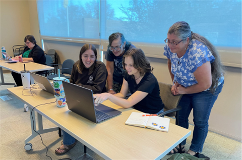 Library youth team staff in training sessions looking at a laptop screen together